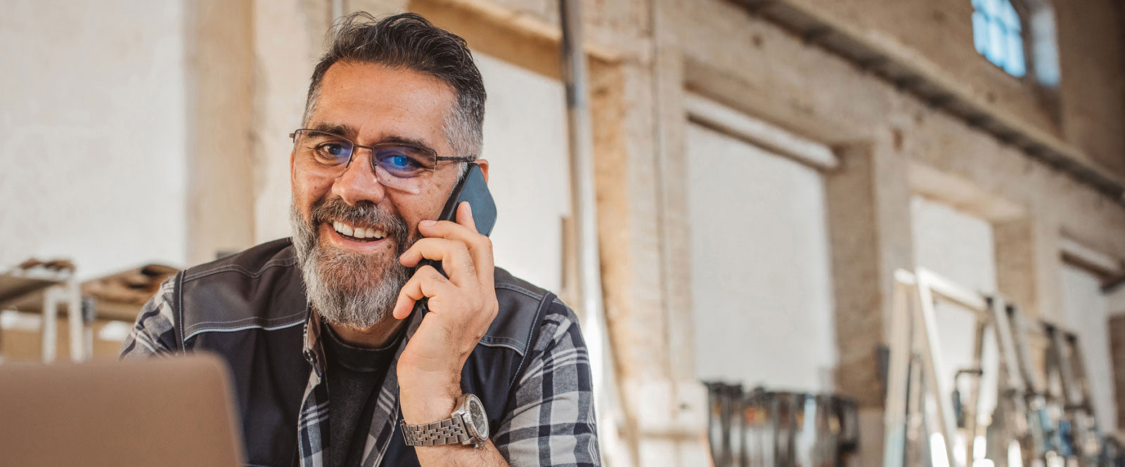 Man talking on a smartphone and looking at a laptop screen 
