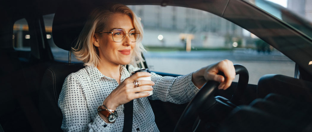 A woman with a paper coffee cup sitting in a car