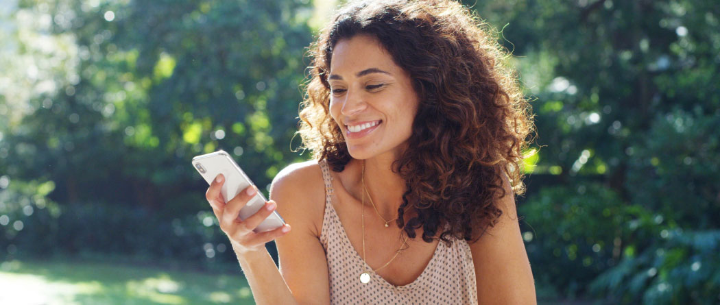 A woman sitting outside and using a smartphone 